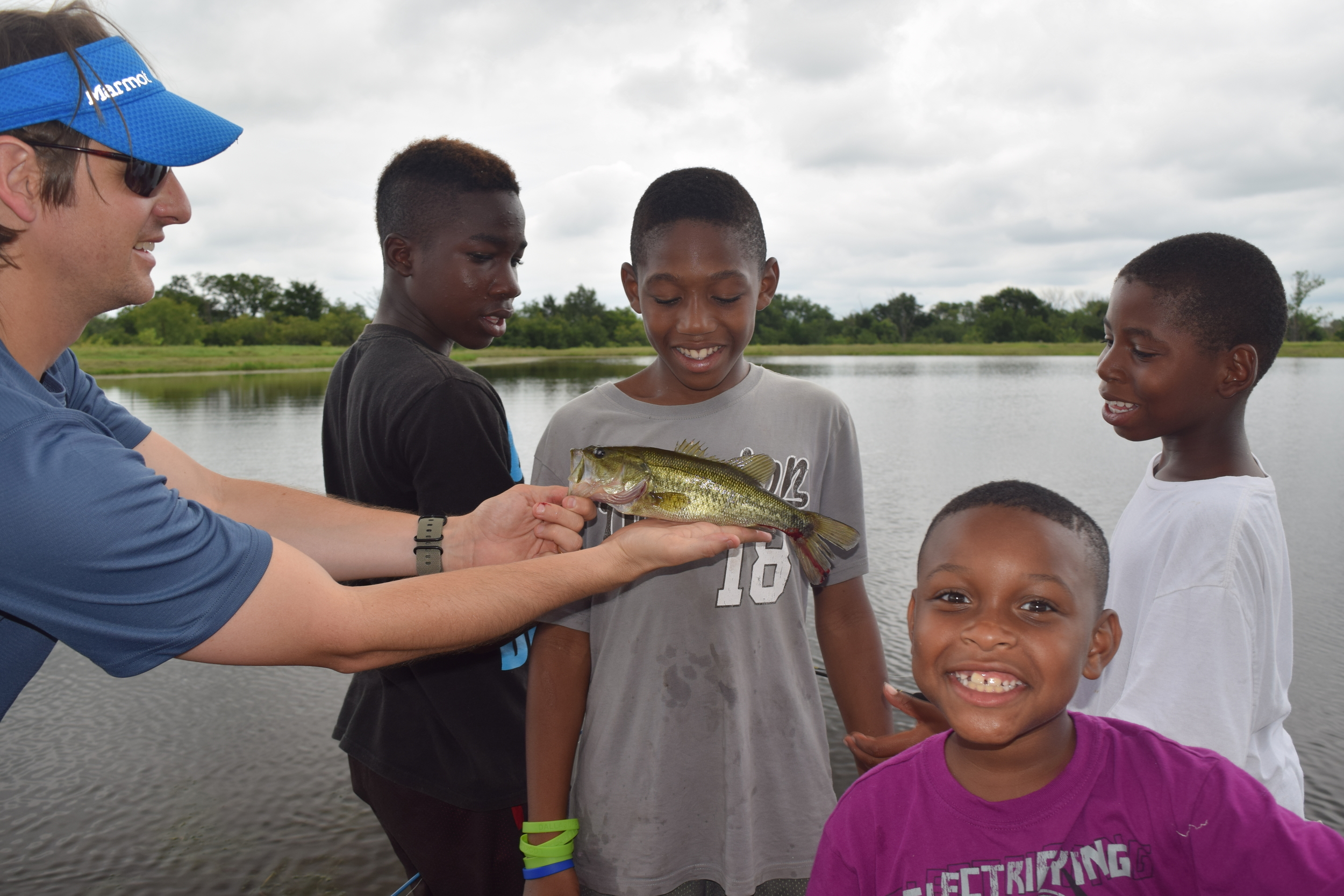Smiling Camp Firewalker participants holding a fish they caught