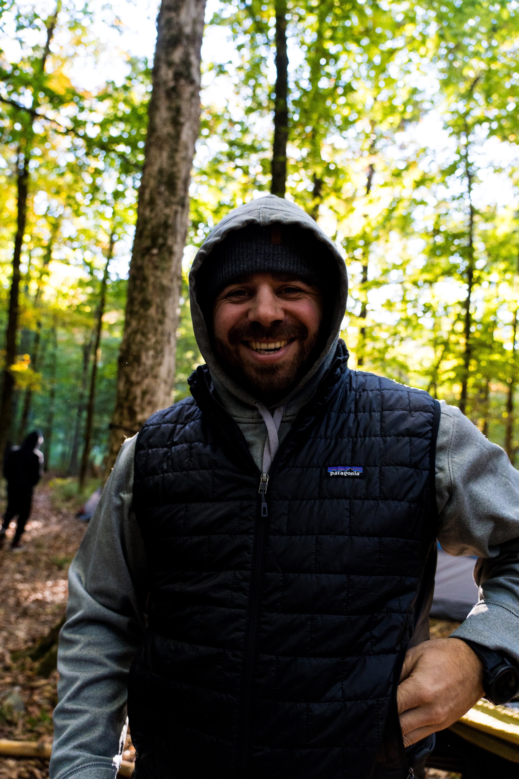 A smiling Camp Firewalker adult leader at a wooded campsite
